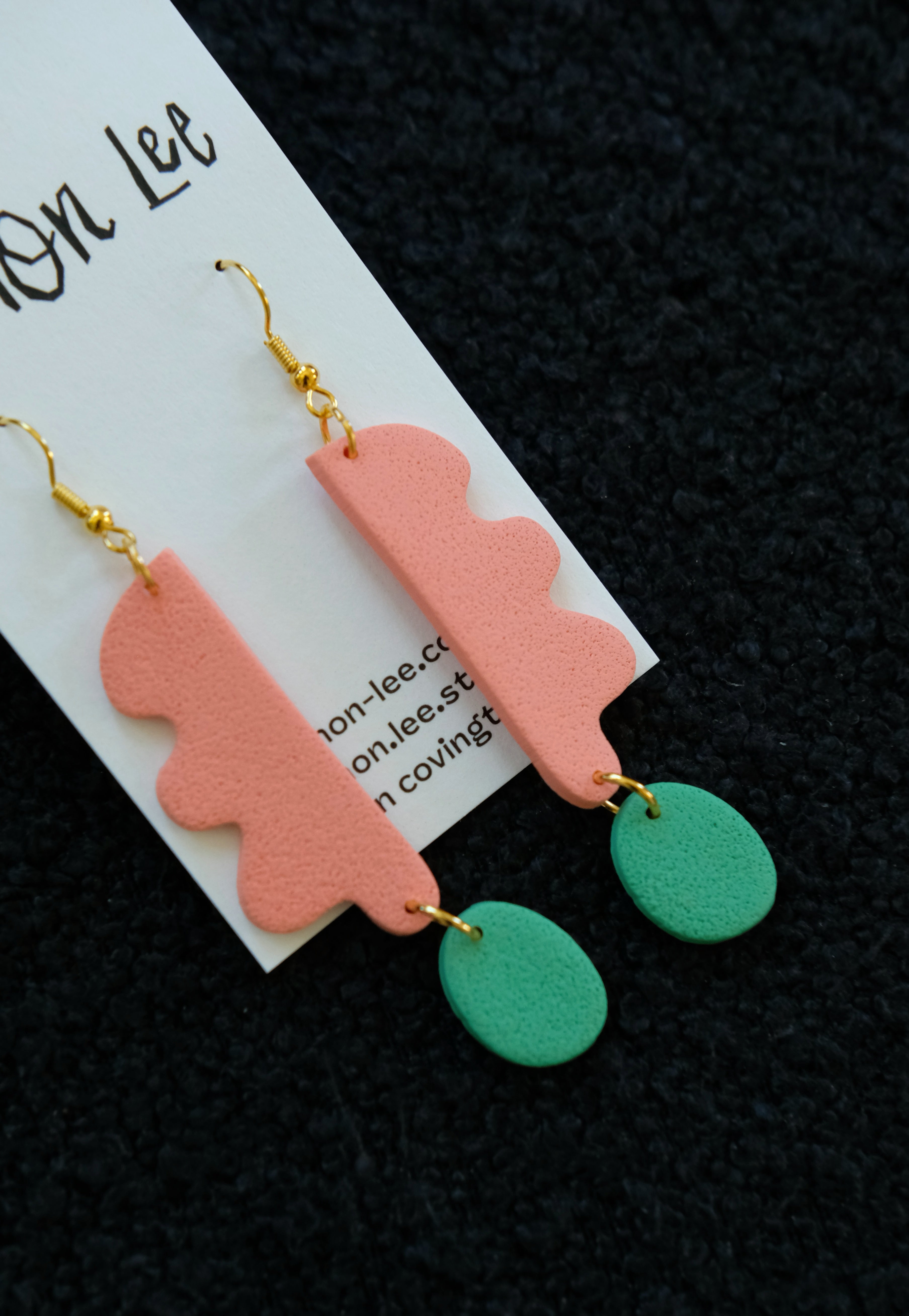 Pair of coral and green earrings on a dark background.