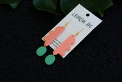 Pair of coral and green earrings on a branded card against a dark background.