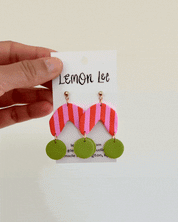 Colorful Pink and Green striped earrings on a branded card against a light background