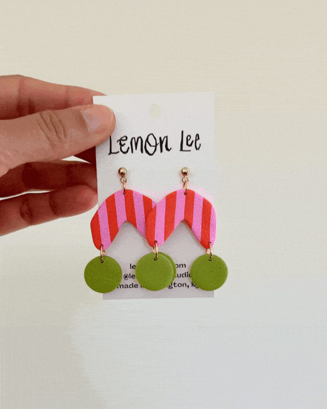 Colorful Pink and Green striped earrings on a branded card against a light background